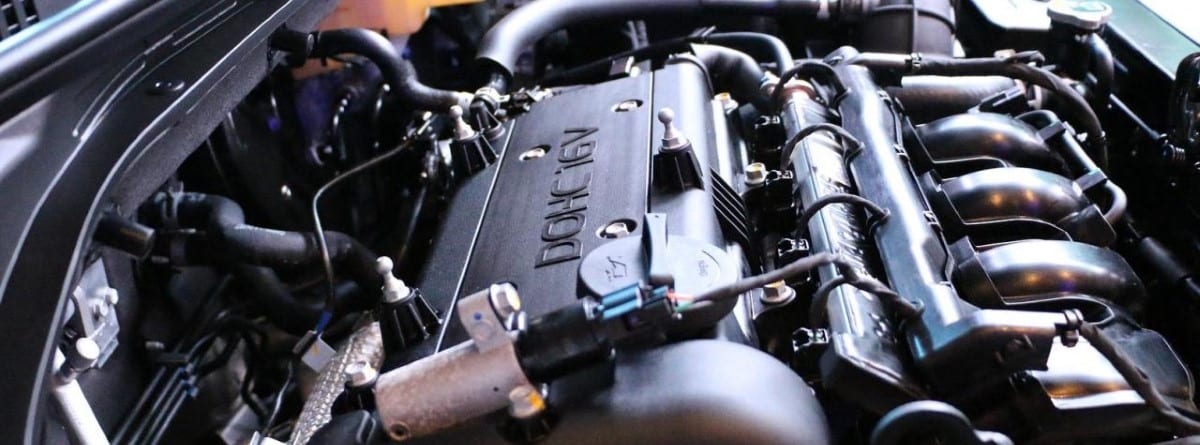 A close-up of a black car engine, showing the camshaft cover, spark plugs and fuel injectors. It is a high quality image with good lighting and shallow depth of field. The message for this image could be: A close-up photograph of a black car engine, showing the camshaft cover, spark plugs and fuel injectors. The image should be well lit and with a shallow depth of field.