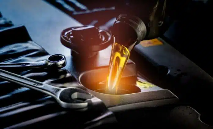 A close-up shot of a mechanic pouring new motor oil into a car engine, backlit by the setting sun, in the style of hyper-realism