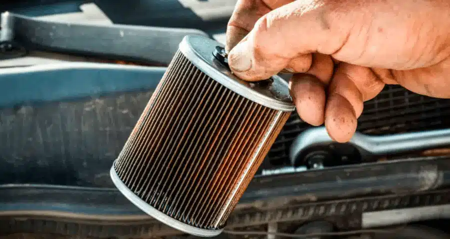 A mechanic inspects a dirty air filter, emphasizing the significance of proper maintenance for optimal car performance. The close-up view demonstrates the obstructed filter, prompting action.