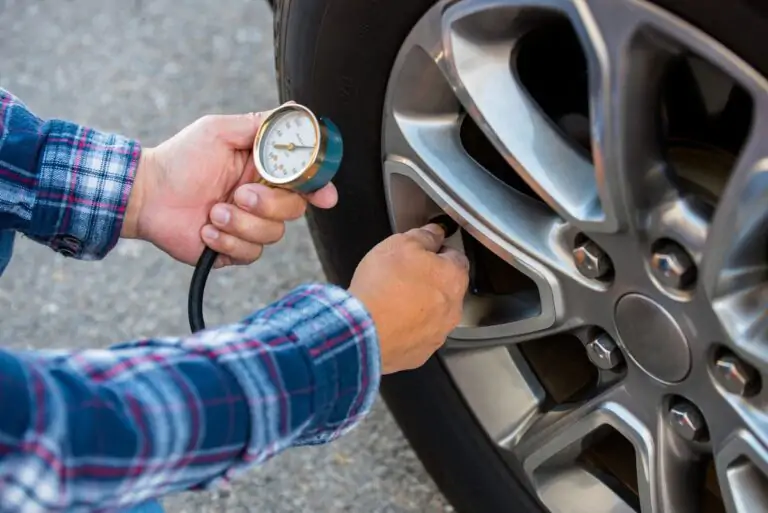 A man checking the air pressure in a car tire